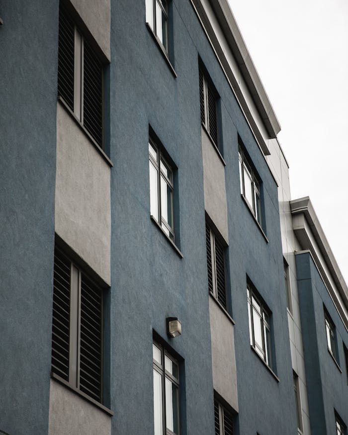 Mastering the First Impression: Your intriguing post title goes here Modern apartment building facade showcasing blue and gray exterior with windows.